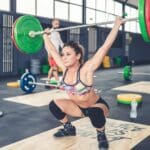 Athletic woman at gym class cross fit training squatting power lifting